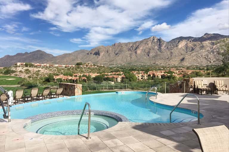 Resort pool and hot tub with mountain views, lounge chairs, and desert landscape