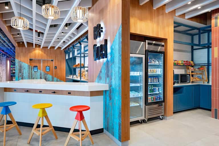 Contemporary hotel snack bar with colorful stools, wood accents, and ocean-themed decor