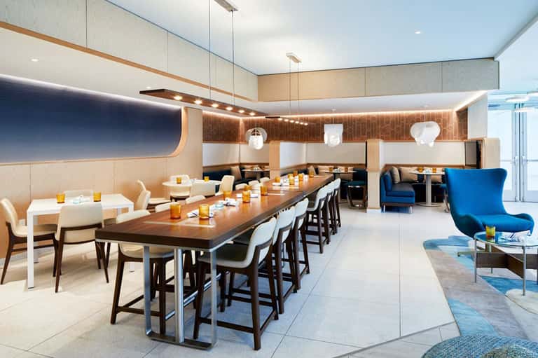 Modern dining lounge with long wooden table, white chairs, and contemporary decor