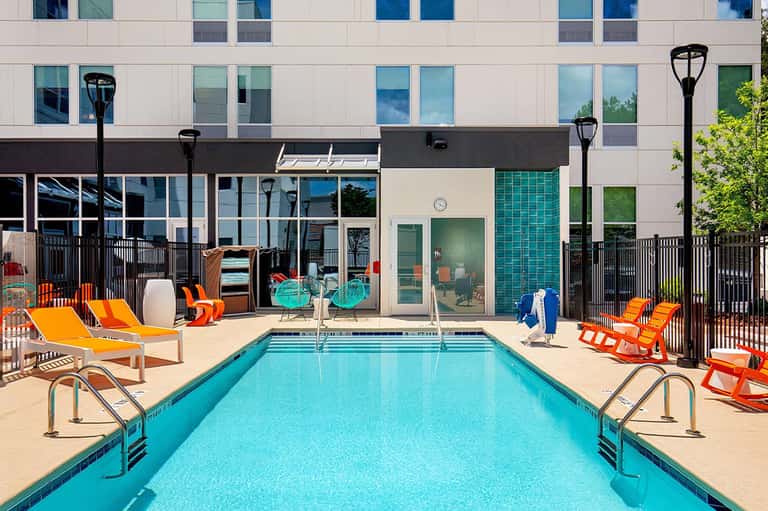 Contemporary resort pool with orange loungers and modern building facade