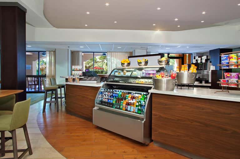 Resort café interior with service counter, pastries, beverages, and seating area with natural lighting