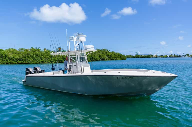Green and white sport fishing boat moored in turquoise tropical waters with mangroves