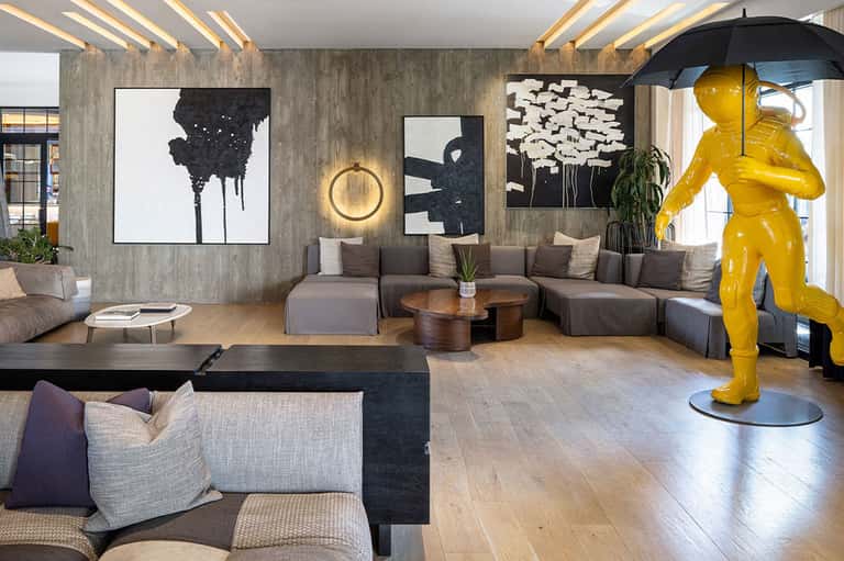 Modern hotel lobby with contemporary art, gray seating, and yellow sculpture