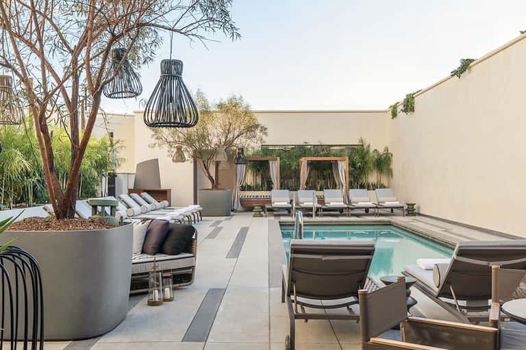 Contemporary courtyard pool area with fire pit, loungers, cabanas, and landscaping