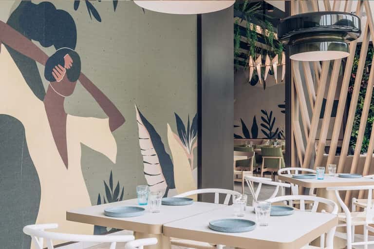 Modern restaurant interior with white tables, botanical wall mural, and contemporary dining setup
