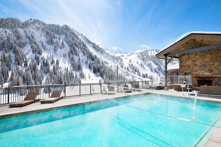 Luxurious outdoor pool with snowy mountains and evergreen forests in the background