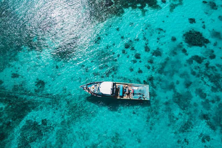 Aerial view of traditional fishing boat on crystal-clear turquoise tropical waters