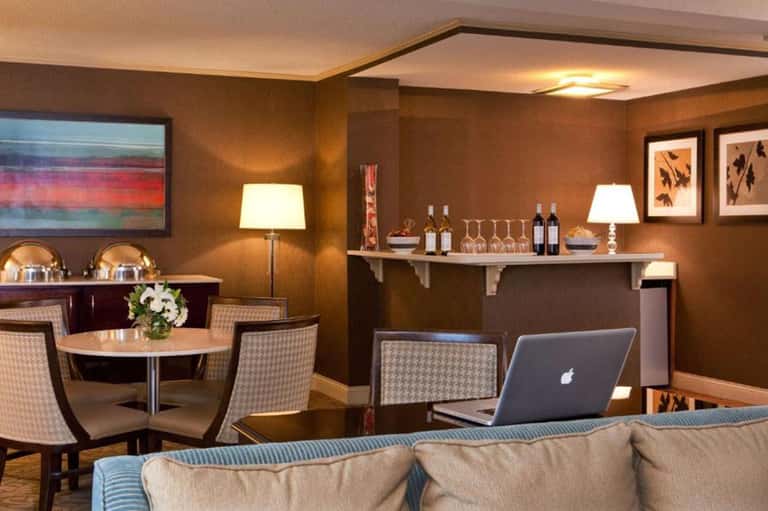 Elegant lounge area with wine bar, fireplace, round table seating, and warm bronze décor