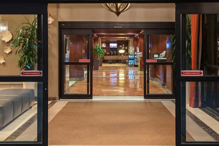 Modern resort lobby entrance with automatic glass doors, polished floors, and decorative plants