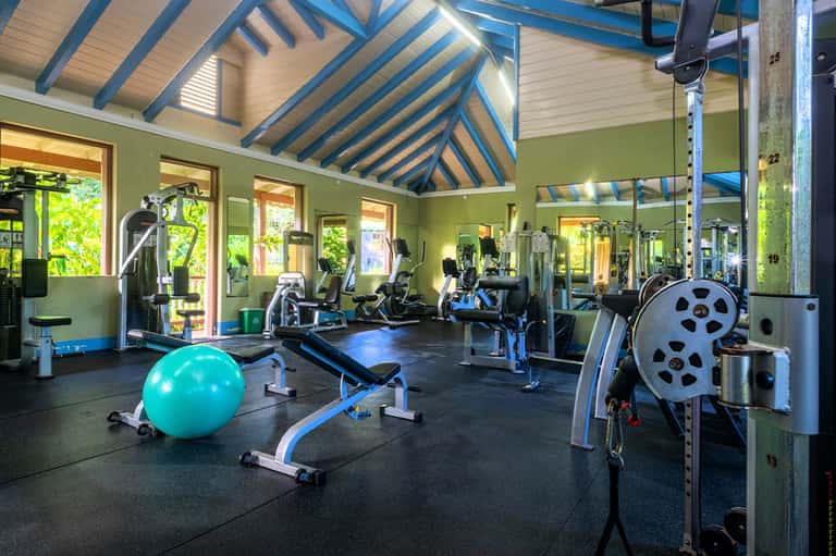 Bright fitness center with exercise equipment and vaulted blue-striped ceiling