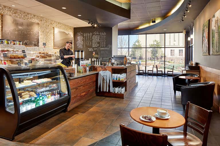 Modern coffee shop interior with pastry display case, counter seating, and large windows