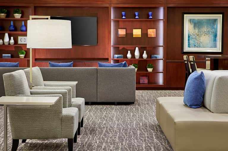 Hotel lounge with wood paneling, comfortable seating, fireplace, shelving, and blue accent pillows