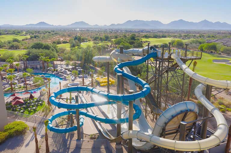 Aerial view of resort water park with blue slides and valley landscape