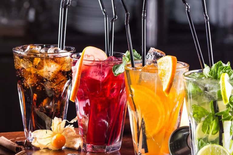 Assorted colorful cocktails with citrus garnishes and fresh mint leaves