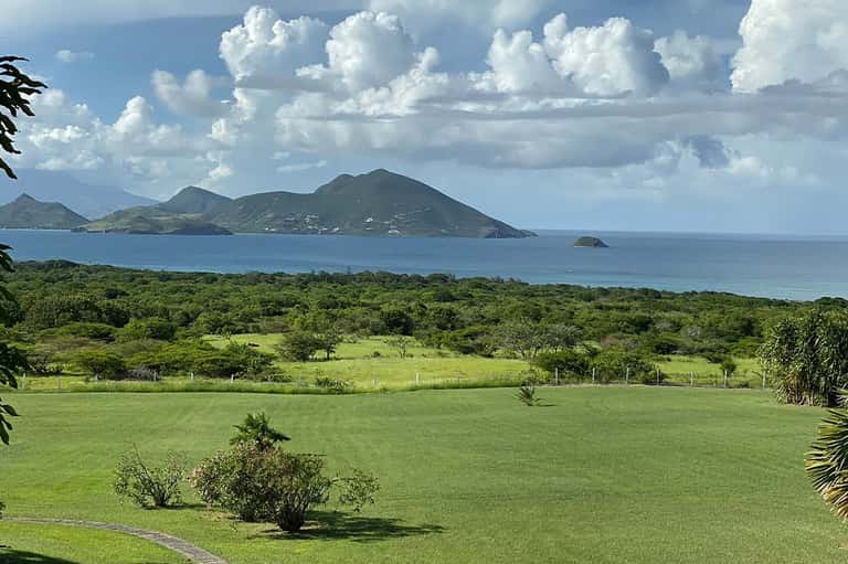 Scenic coastal landscape with volcanic islands, green fields, and ocean horizon