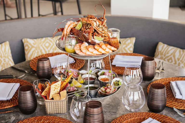 Elegant seafood tower display with lobster, shrimp, and sides on dining table setting