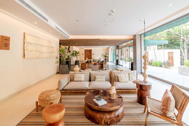 Upscale resort lobby with beige sofa, wooden accents, and ocean view through glass doors