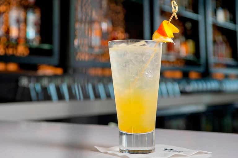 Refreshing citrus cocktail with orange peel garnish served at beachside bar