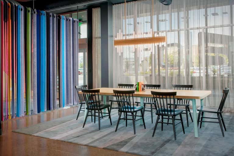 Modern hotel meeting space with colorful fabric panels, wooden table, and glass walls