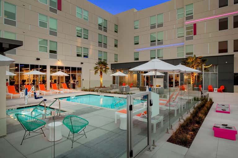 Modern resort pool deck with bright turquoise water, umbrellas, and contemporary building architecture
