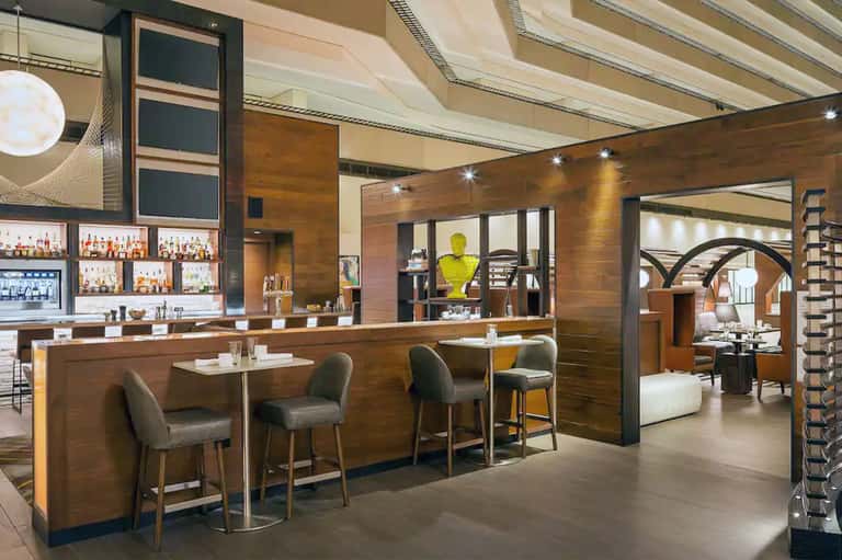Contemporary hotel bar and lounge with wood paneling, retractable ceiling, and open floor plan