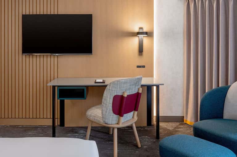 Modern hotel room with desk, flat-screen TV, and contemporary furnishings