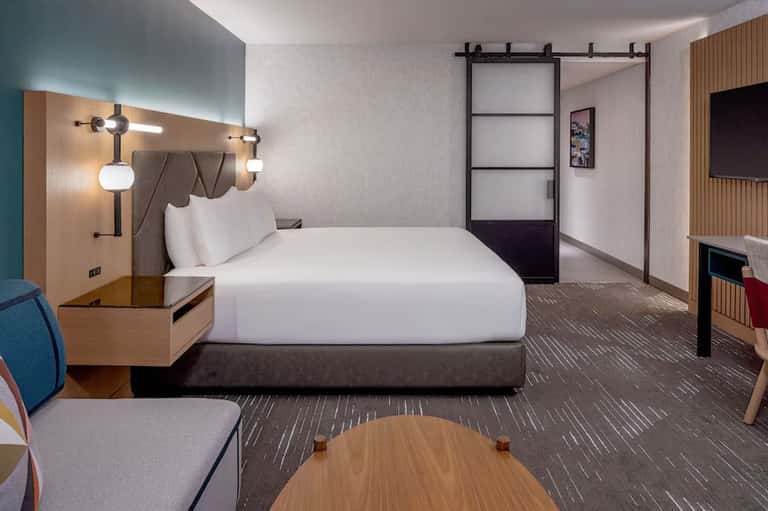 Modern hotel bedroom with contemporary lighting, white bedding, and minimalist design elements