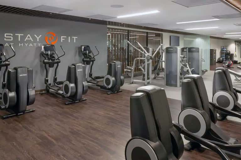 Modern fitness center with cardio equipment, StayFit signage and exercise machines on wooden floor