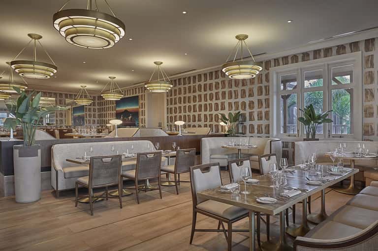 Upscale restaurant dining room with geometric wallpaper, modern lighting, and contemporary furniture