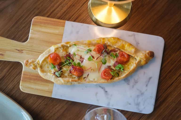 Gourmet flatbread pizza with fresh toppings on marble serving board