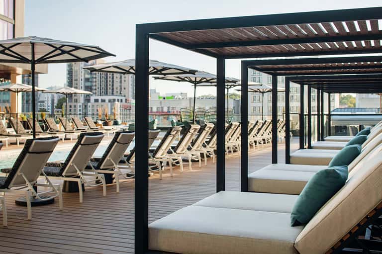 Upscale rooftop terrace with modern lounge chairs, umbrellas, and city skyline views