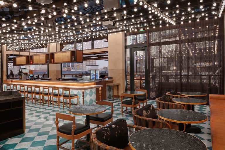 Contemporary coffee shop interior with decorative ceiling lights, bar counter, and geometric flooring