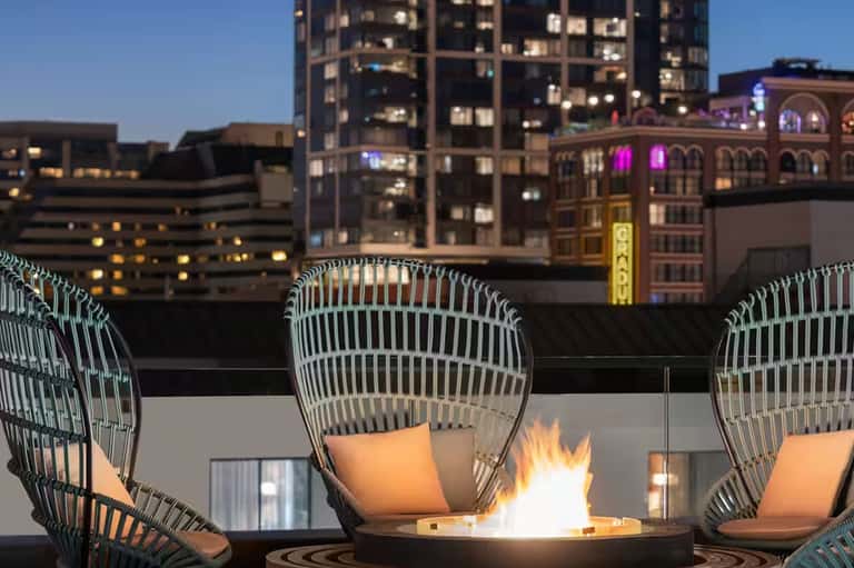 Rooftop firepit lounge overlooking illuminated downtown city skyline at dusk