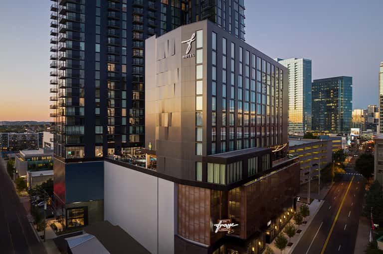Modern hotel building at dusk with illuminated facade in urban downtown setting