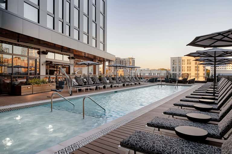 Rooftop pool at urban hotel with city skyline views, lounge chairs, and modern architecture