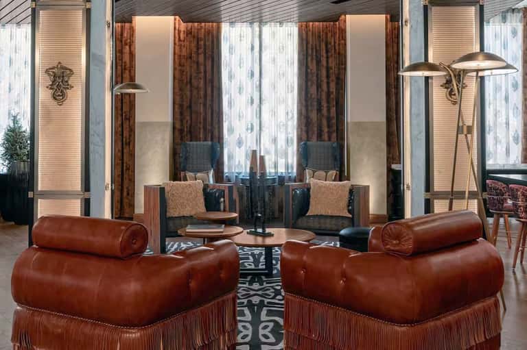 Luxurious lounge with cognac leather seating, modern lamps, and floor-to-ceiling windows