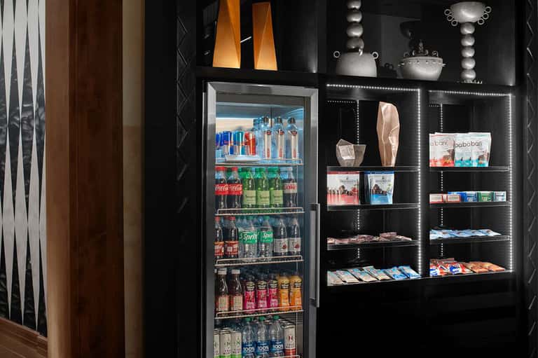 Modern beverage station with refrigerator, black shelving, and retail products
