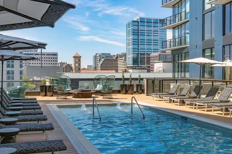 Urban rooftop pool deck with lounge chairs, umbrellas, and city skyline views