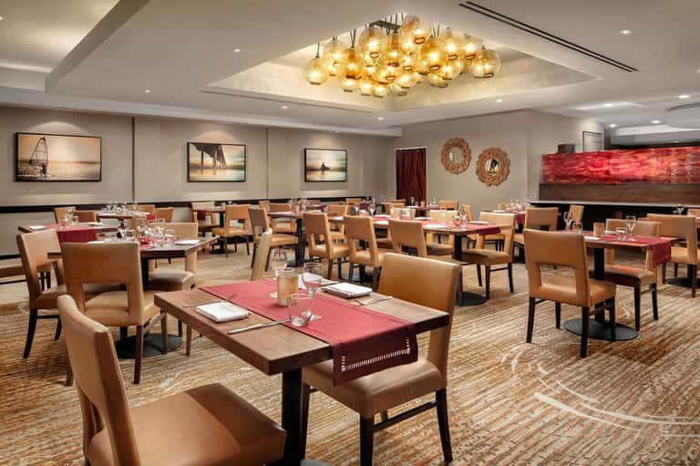 Elegant resort dining room with leather chairs, warm lighting, and ocean-themed wall art