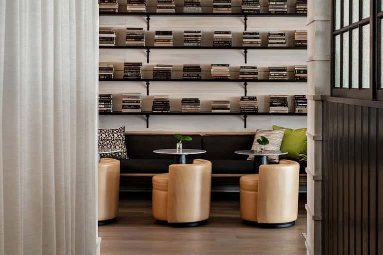 Luxury lounge interior with black sofa, tan barrel chairs, and floating bookshelves above