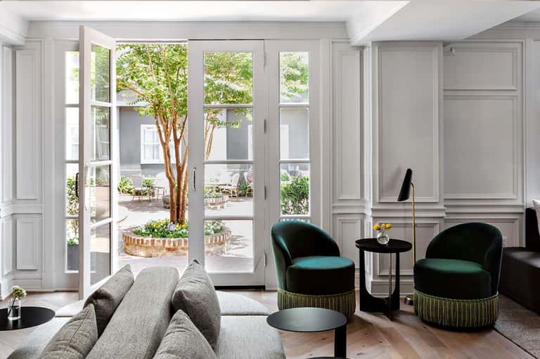 Elegant living room with floor-to-ceiling glass doors opening to courtyard garden view