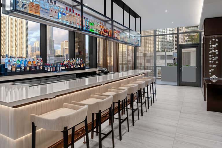 Upscale rooftop bar with city skyline views, white leather seating, and premium liquor display