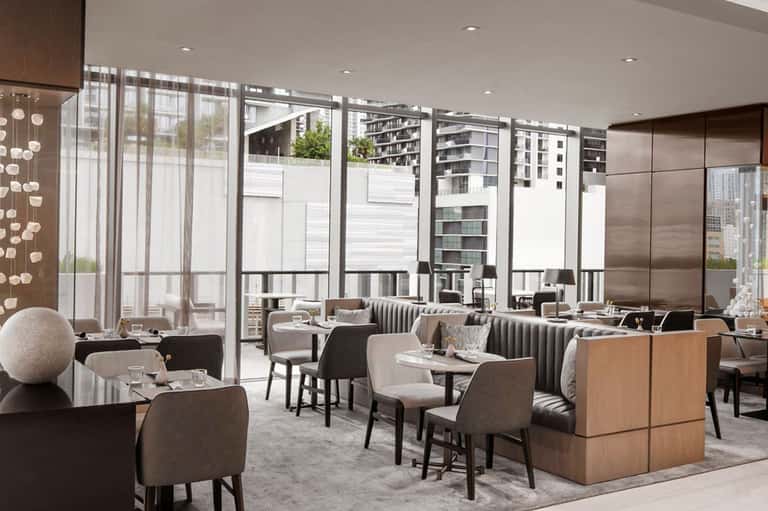 Modern restaurant interior with contemporary seating, floor-to-ceiling windows, and city views