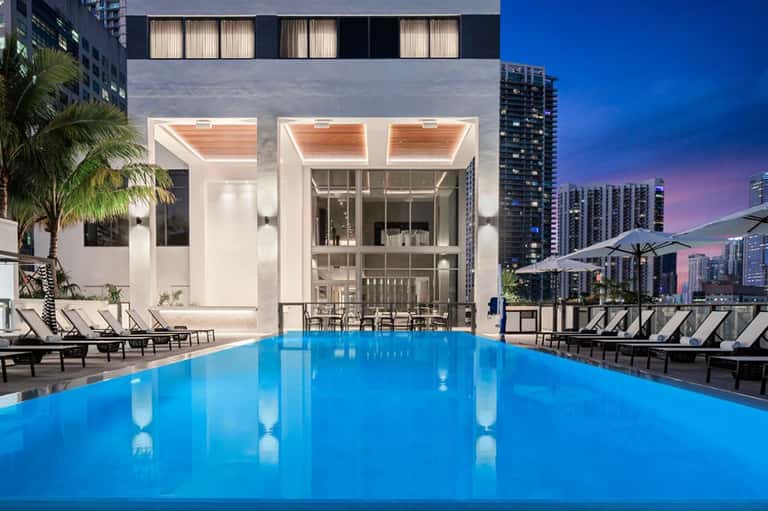 Modern rooftop pool with city skyline at dusk and lounge seating