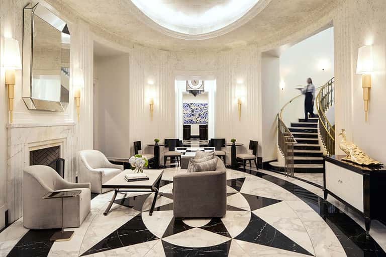 Elegant marble lobby with fireplace, patterned floor, grand staircase, and modern furnishings