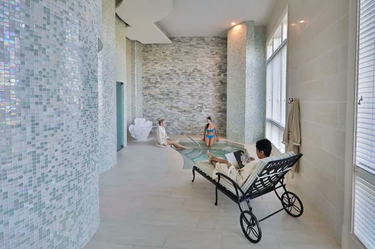 Modern spa area with mosaic tile walls, hot tub, and guests relaxing indoors