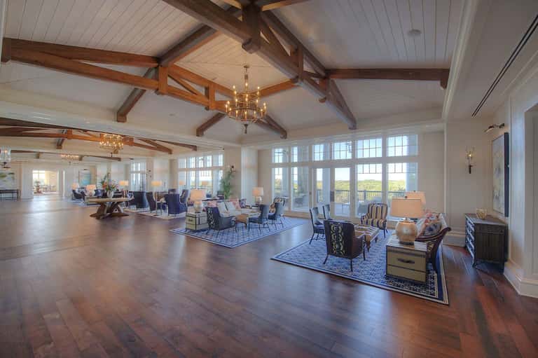 Grand resort lobby with exposed beam ceiling, chandeliers, hardwood floors, and ocean view doors