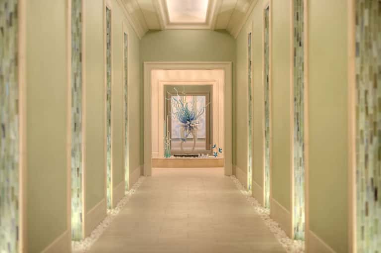 Elegant hallway with cream walls, recessed lighting, and blue floral arrangement in window niche