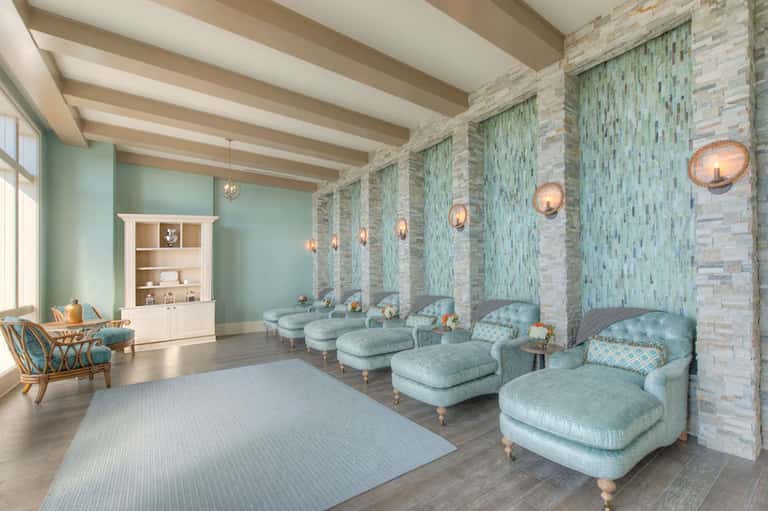 Spa relaxation room with mint-green accent walls, light blue loungers, fireplace, and pendant lighting