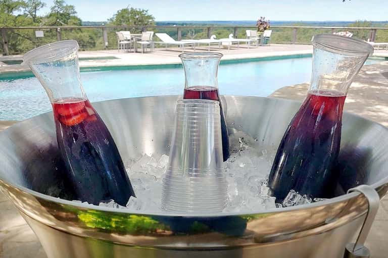 Three tropical cocktails with ice on table overlooking resort pool and landscape
